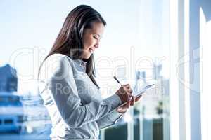 Smiling businesswoman writing on notebook