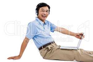Portrait of cheerful man using laptop while listening music