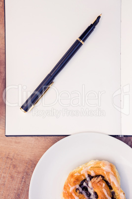Pen and notepad by sweet food in plate
