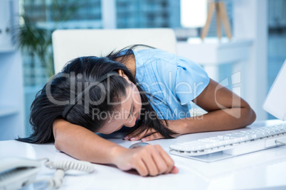 Tired businesswoman sleeping at her desk