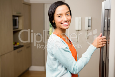 Smiling brunette with hand on refrigerator