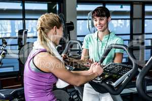 Fit woman doing exercise bike with trainer