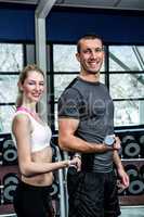 Smiling fit couple lifting dumbbells