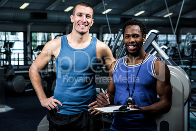 Muscular man with trainer smiling at camera