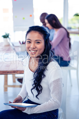 Portrait of businesswoman holding tablet PC with colleagues in b