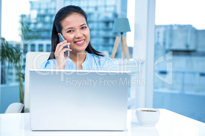 Smiling businesswoman on phone using laptop