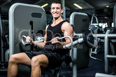 Smiling muscular man using exercise machine