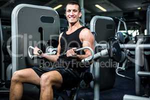 Smiling muscular man using exercise machine