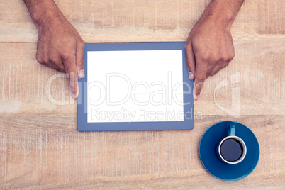 Hand holding on digital tablet over table by coffee