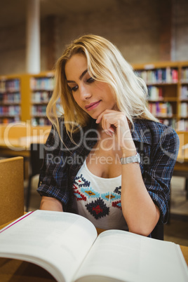 Smiling student reading a book at table