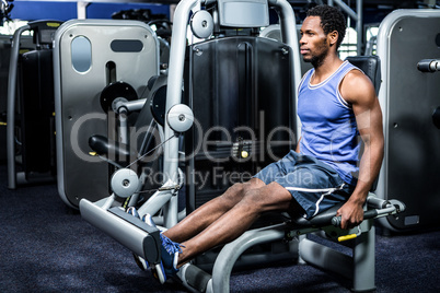 Serious muscular man using exercise machine