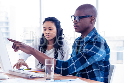 Serious businessman discussing with businesswoman over computer