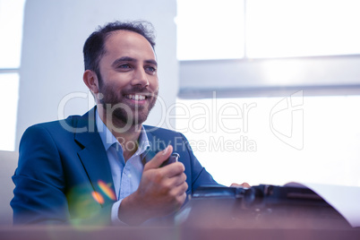 Happy businessman looking away while sitting in office