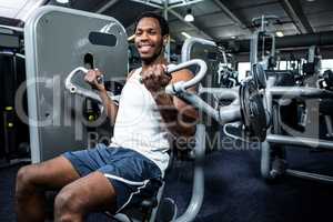 Smiling muscular man using exercise machine