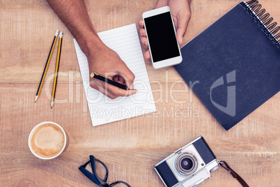 Overhead view of businessman writing on notepad