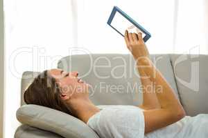 Happy woman using tablet on sofa