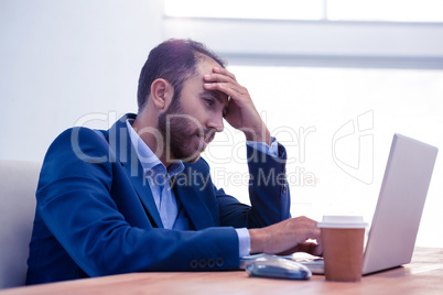 Bored man working on laptop in office