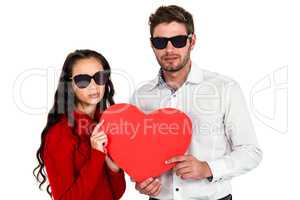 Portrait of couple with sunglasses holding paper heart