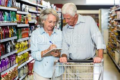 Smiling senior couple with cart checking list