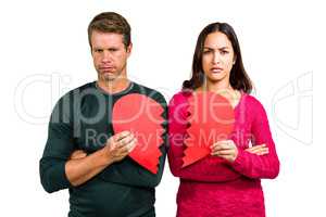 Portrait of serious couple holding cracked heart shape