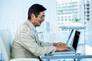 Smiling asian businessman working on laptop