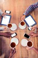 Business colleagues using technologies at desk while holding cof