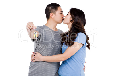 Young man kissing girlfriend while showing keys