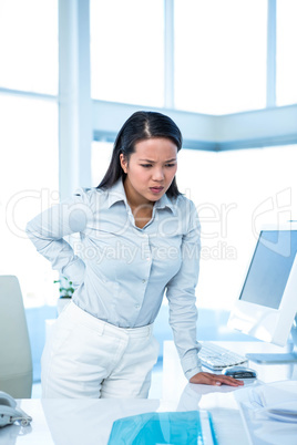 Frowning businesswoman with back ache standing