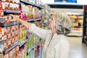 Senior woman picking food from aisle