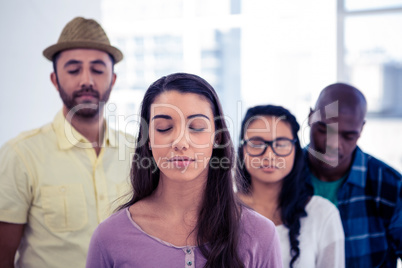 Young businesswoman and team with eyes closed