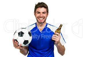 Smiling man holding football and beer bottle