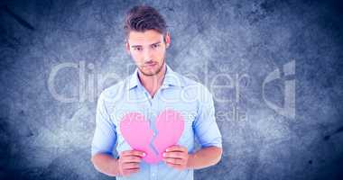 Composite image of sad man holding a broken heart