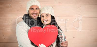 Composite image of smiling couple holding paper heart