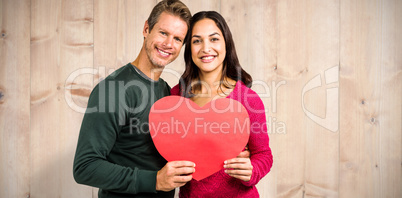 Composite image of portrait of smiling couple holding heart shap