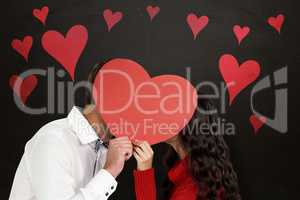Composite image of couple covering faces with paper heart