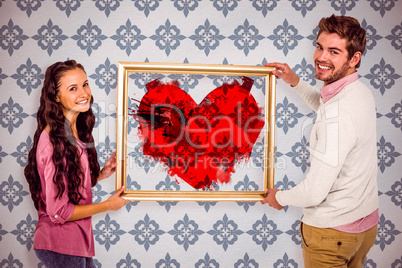 Composite image of smiling couple holding picture frame