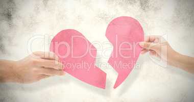 Composite image of hands holding two halves of broken heart