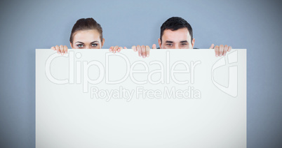 Composite image of business partners hiding behind a sign
