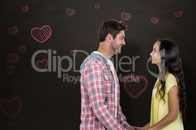 Composite image of smiling couple holding hands and looking at e