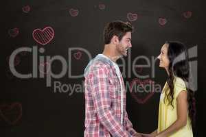 Composite image of smiling couple holding hands and looking at e