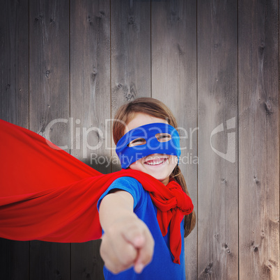 Composite image of smiling masked girl pretending to be superher