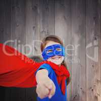 Composite image of smiling masked girl pretending to be superher