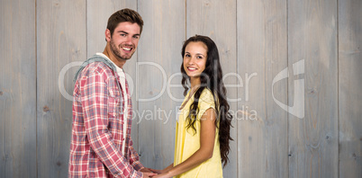 Composite image of smiling couple holding their hands and lookin