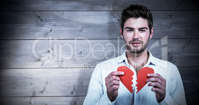 Composite image of sad man holding heart halves