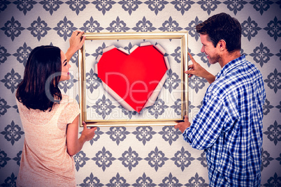 Composite image of happy couple holding picture frame