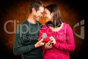 Composite image of happy couple holding gift box