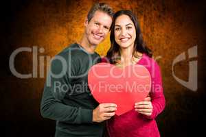 Composite image of portrait of smiling couple holding heart shap