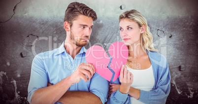 Composite image of couple holding two halves of broken heart