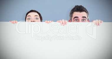 Composite image of man and woman hiding behind a white board wit