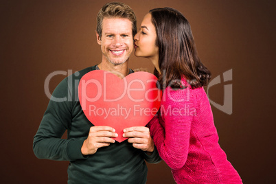 Composite image of woman kissing boyfriend with red heart shape